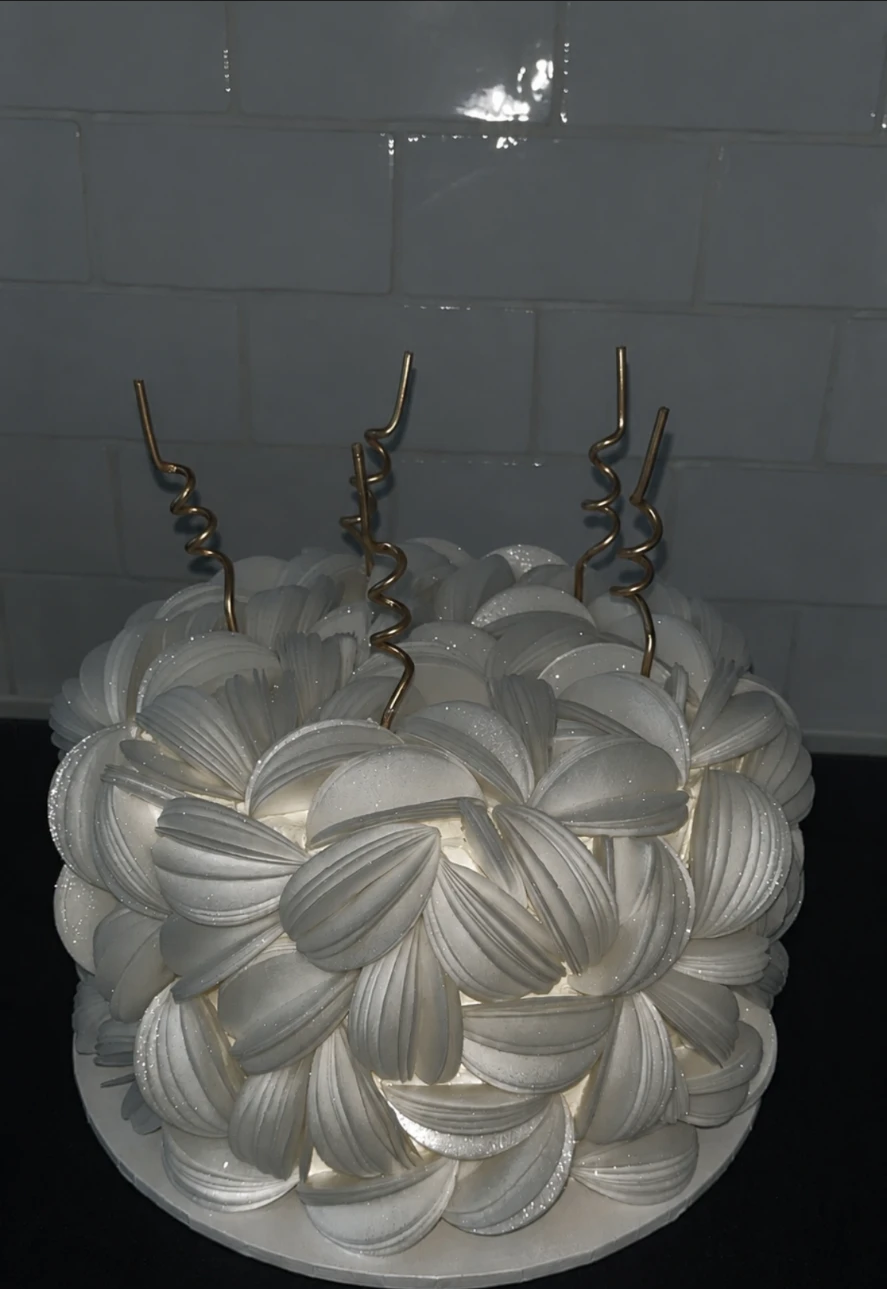 White petal-textured buttercream cake with shimmer and gold swirl candles